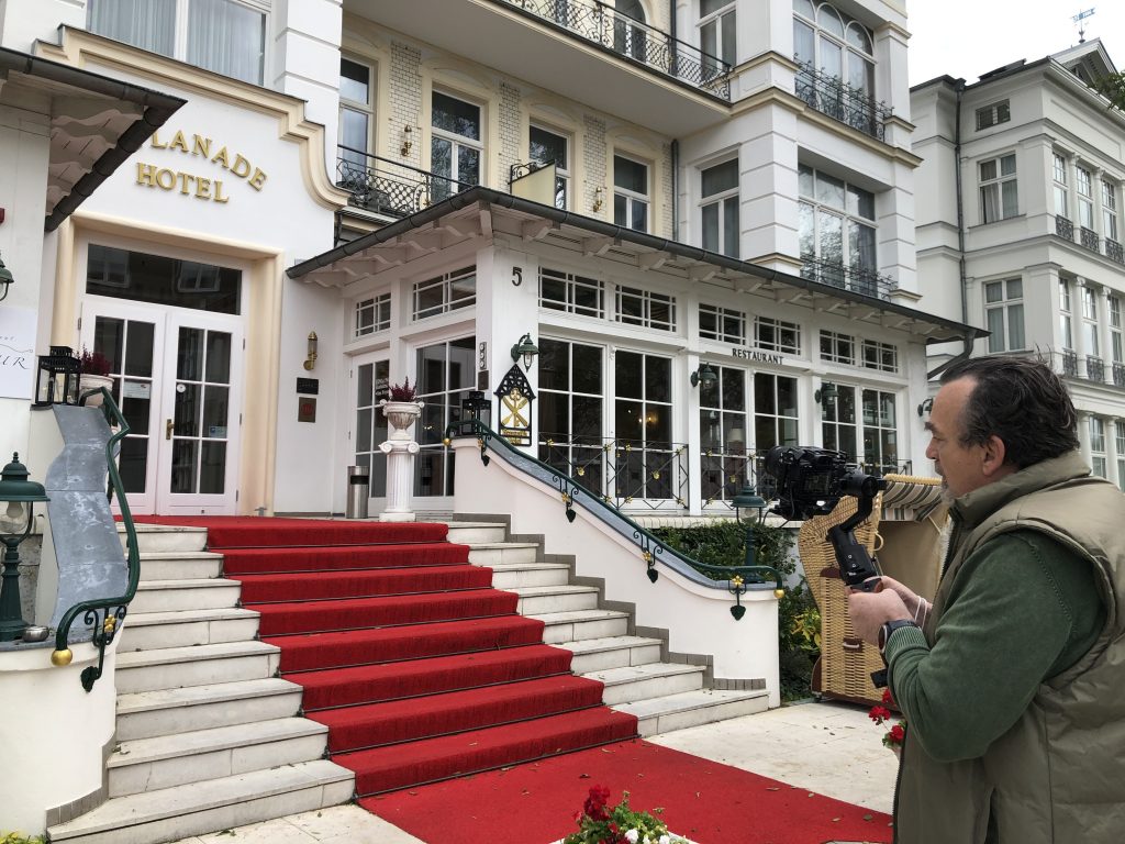 Hotelfilm Produktion ah-tv Kameramann mit Kamera beim Shooting vor dem Hotel Seetelhotels